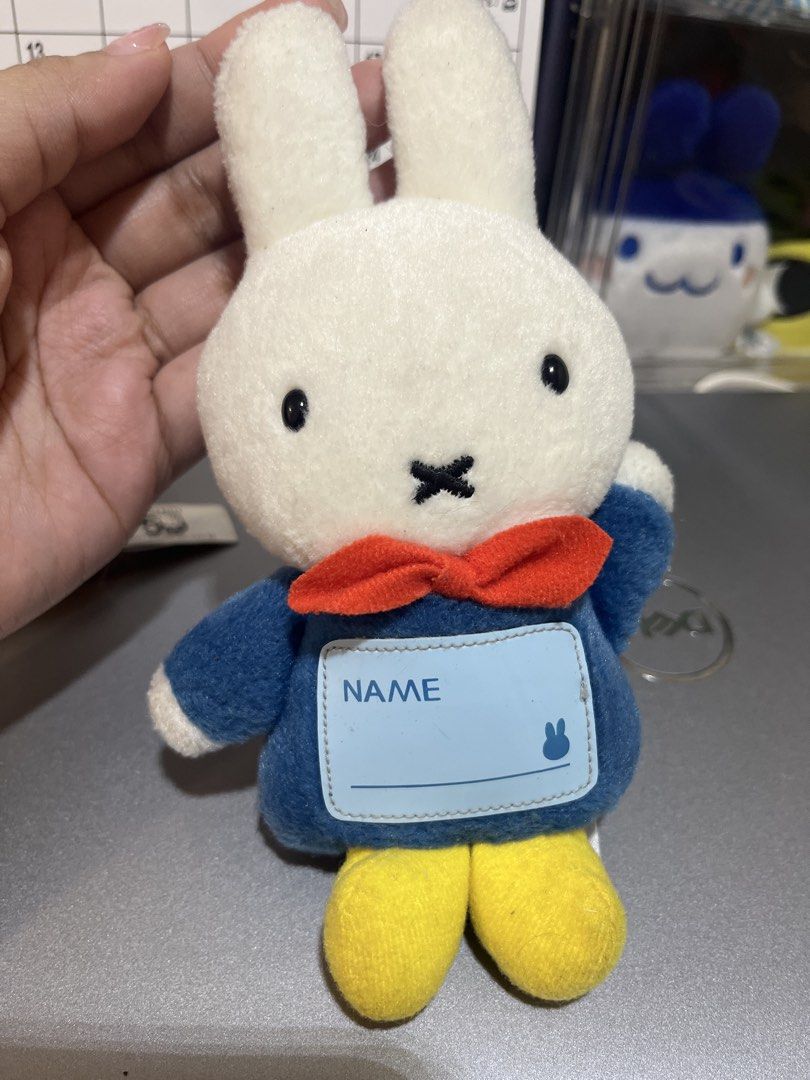 Miffy Plush Toy Keychain by Sekiguchi (Category: Plushies & Soft Toys) located in Candelaria. Submitted by wishizen (Listing ID 1432928133, Image 1). Description: - Adorable Miffy plush toy - Features a blue outfit and red bow tie - Includes yellow feet - Has a label on the front - Tag on the back reads "Huis Ten Bosch" and "Sekiguchi Since 1918" .