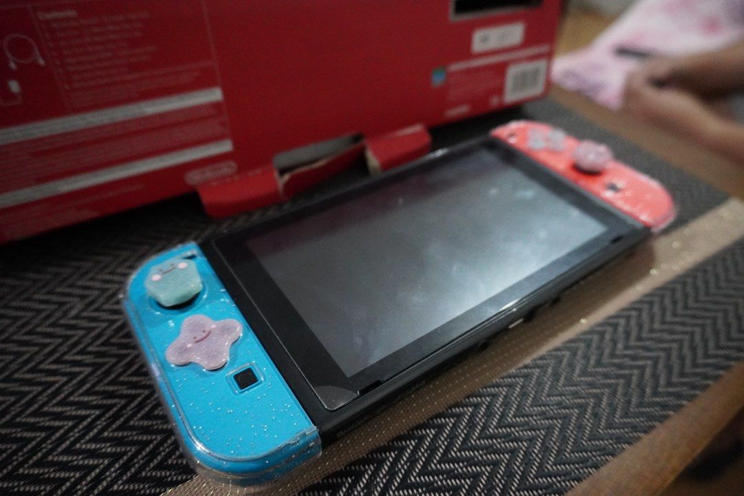 Nintendo Switch 1 with free Animal Crossing (Category: Nintendo) located in Quezon City. Submitted by katherine_is_selling (Listing ID 1432934516, Image 3). Description: - Nintendo Switch console with blue and red Joy-Cons - Includes the original box and all original accessories - Comes with a copy of Animal Crossing: New Horizons - Joy-Cons have protective cases - Screen displays the game library - Box contents: Console, Joy-Con controllers, doc