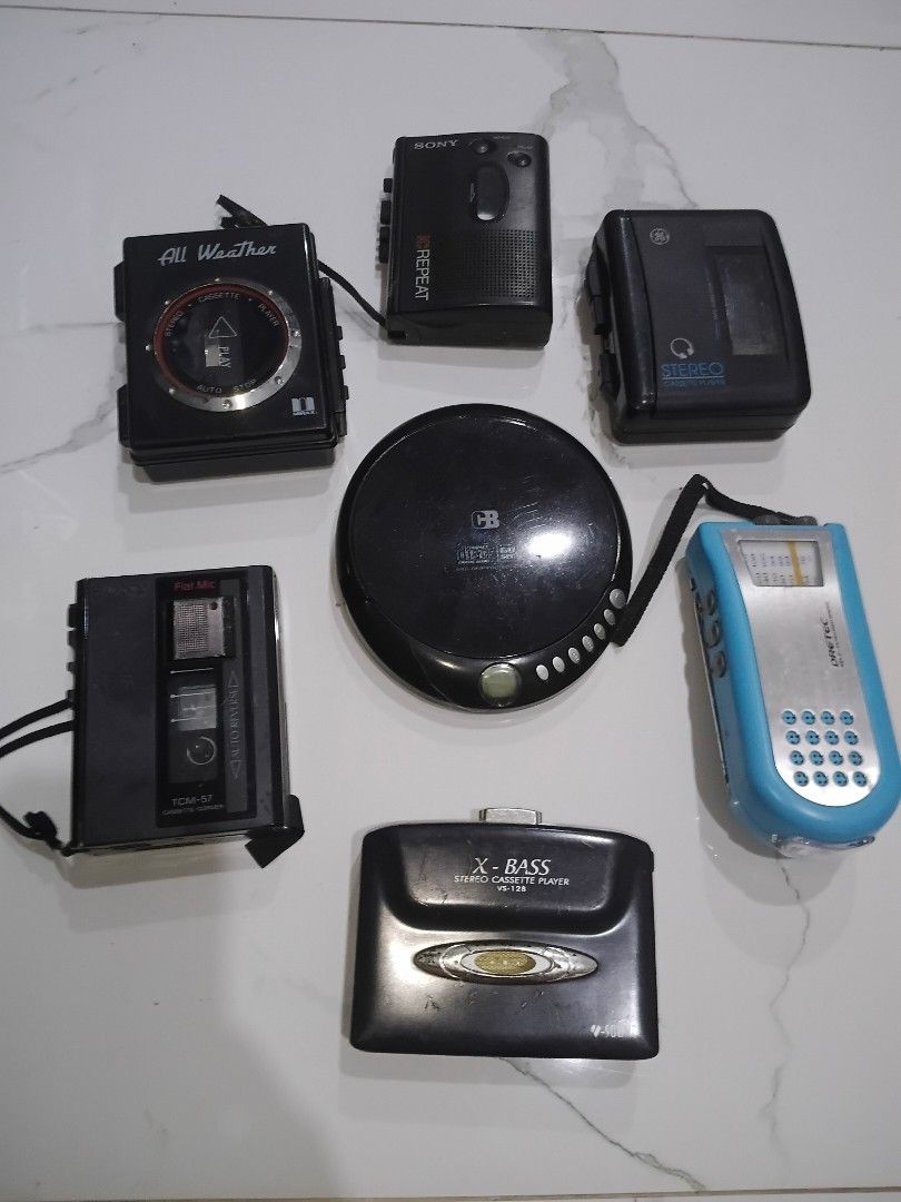 Assorted Portable Audio Players (Category: Portable Music Players) located in Manila. Submitted by daisuki8 (Listing ID 1433090759, Image 1). Description: Collection of portable audio players including a CD player, cassette players, and a radio. Includes a Sony cassette player with a repeat function, and an X-Bass cassette player. Also includes a blue and silver radio. All items are black. AS IS WHERE IS CONDITION FOR TAKE ALL .