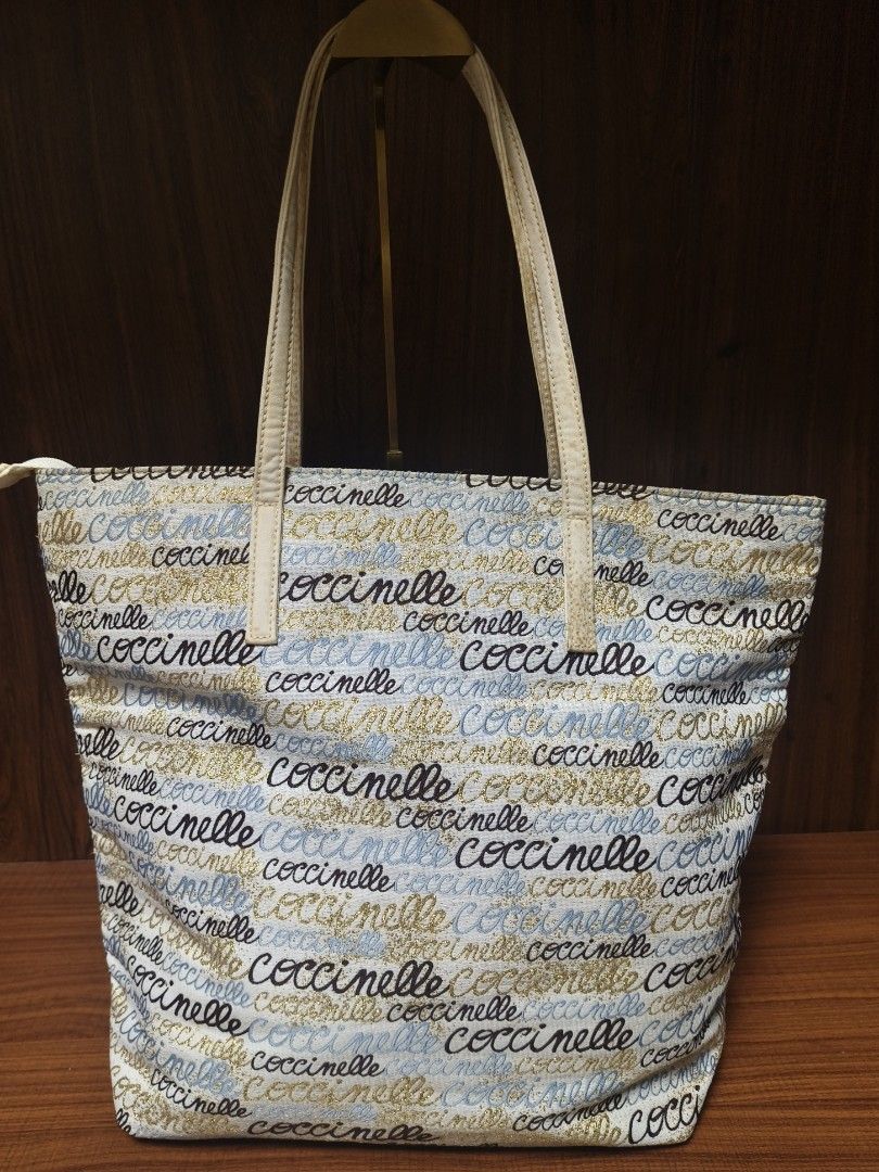 Coccinelle Logo Print Tote Bag (Category: Luxury Bags & Wallets) located in Baguio. Submitted by PreiLoveMaria (Listing ID 1433106091, Image 2). Description: Coccinelle Logo Print Tote Bag featuring a vibrant, all-over script pattern in black, light blue, and shimmering gold-perfect for adding a pop of personality to your everyday look. ✔️ Spacious trapezoidal tote – ideal for daily use or travel ✔️ Eye-catching multi-color logo print ✔️ Durable 
