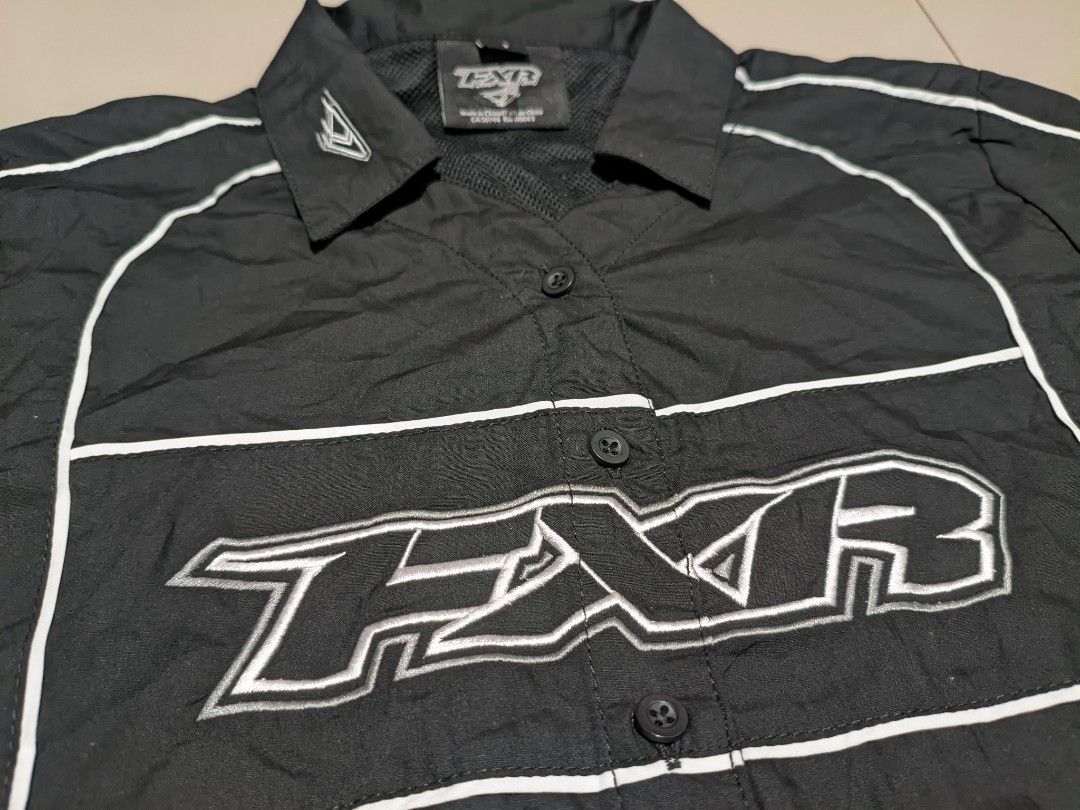 FXR Short Sleeve Shirt (Category: Blouses) located in Caloocan City. Submitted by wupeeram (Listing ID 1433135639, Image 3). Description: - Black short sleeve shirt - White FXR logo and accents - Collared neckline - Button-up front - FXR logo on front, back, and sleeves - Size: L26, W18, W20 - Brand new condition - Made in China.