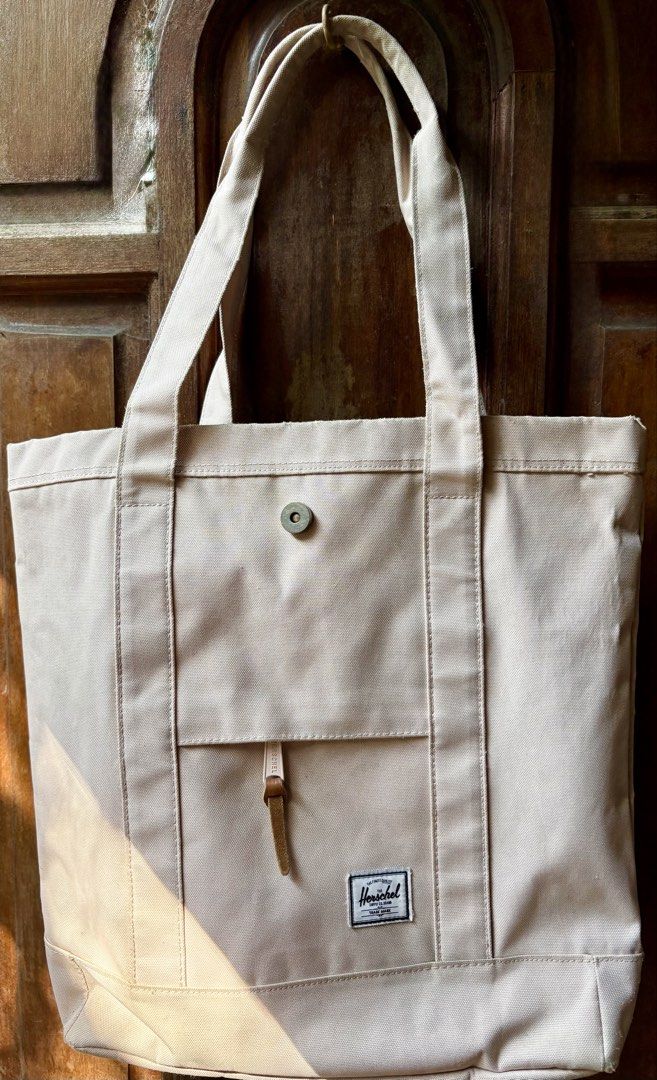 Herschel Supply Co. Tote Bag (Category: Tote Bags) located in Cebu City. Submitted by claregalon (Listing ID 1433004059, Image 1). Description: - Herschel Supply Co. tote bag - Neutral beige color - Front pocket with leather strap and snap closure - Dual top handles - Made of sturdy canvas material - Herschel Supply Co. label on front.