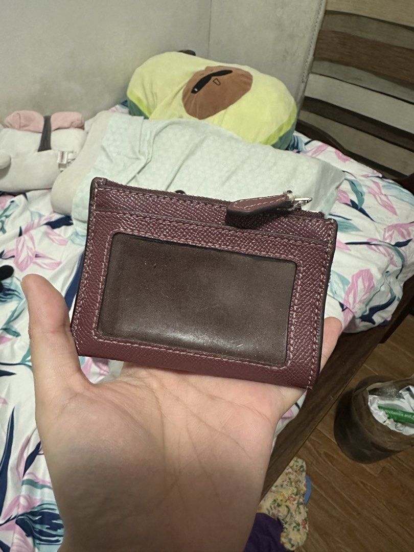 Original Coach Card Holder (Category: Wallets & Card holders) located in Quezon City. Submitted by jieunahiu (Listing ID 1433155014, Image 3). Description: Heavily used!! Bought in Coach outlet Jan 2020. Please see pics Theres a lot of cracks on the leather Coach card holder in a burgundy color. Features a zip closure and multiple card slots. Includes a clear ID window on the back. The Coach logo is visible on the front. Comes with care instructi