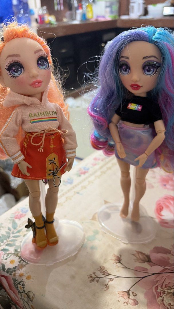 Rainbow High Fashion Dolls (Category: Kids Toys) located in Nagcarlan. Submitted by kateelove09 (Listing ID 1433177735, Image 3). Description: - Rainbow High dolls available! - Doll 1: Orange hair, pink hoodie, orange skirt, with stand. - Doll 2: Blue and pink hair, black top, skirt, with stand..