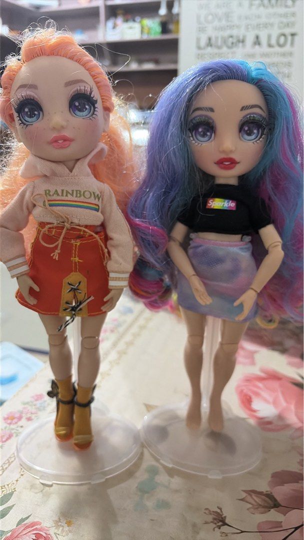 Rainbow High Fashion Dolls (Category: Kids Toys) located in Nagcarlan. Submitted by kateelove09 (Listing ID 1433177735, Image 2). Description: - Rainbow High dolls available! - Doll 1: Orange hair, pink hoodie, orange skirt, with stand. - Doll 2: Blue and pink hair, black top, skirt, with stand..