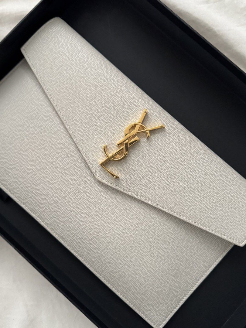 Saint Laurent (YSL) Uptown Envelope Clutch (Category: Luxury Bags & Wallets) located in Taguig. Submitted by czarcloset (Listing ID 1433071205, Image 1). Description: - Personal preloved - Authentic Saint Laurent Envelope Clutch - Cream color - Iconic gold YSL logo - Includes box - Entrupy certificate of authenticity included - Black interior lining with Saint Laurent Paris logo - Perfect for any occasion.