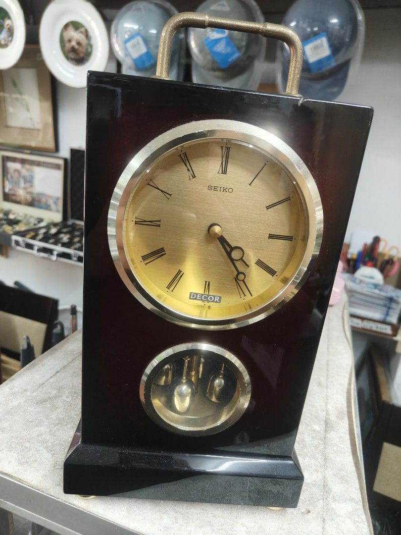Seiko Decor Pendulum Clock (Category: Clocks) located in Cavite. Submitted by sevillajoh71978 (Listing ID 1433081465, Image 1). Description: - Vintage Seiko Decor pendulum clock - Gold-toned clock face with Roman numerals - Features a pendulum display - Dark wood finish with handle - Battery compartment and mechanism visible.