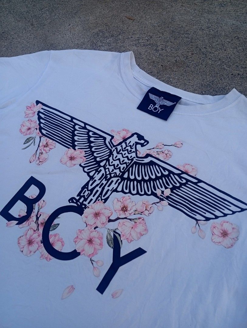 Boy London Eagle Print T-shirt (Category: Tshirts & Polo Shirts ) located in Taguig. Submitted by aron_robrigado (Listing ID 1429781211, Image 3). Description: White Boy London T-shirt featuring an eagle and floral print design. The shirt has a crew neck and short sleeves. The size is S. The tag shows the brand's website. The shirt is made of 100% cotton. The shirt has a tag with washing instructions..