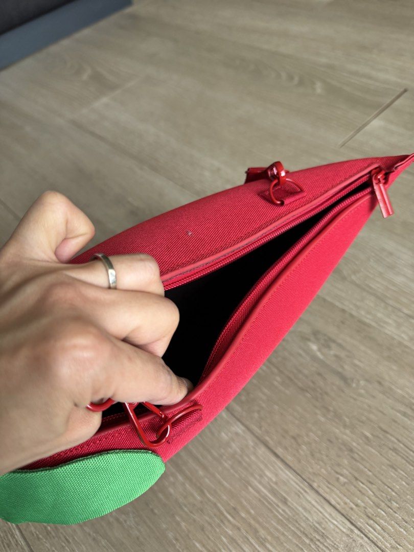 Chili Pepper Crossbody Bag (Category: Cross-body Bags) located in San Juan City. Submitted by steffchua (Listing ID 1429679782, Image 2). Description: Unique crossbody bag shaped like a chili pepper. Features a red exterior with a green leaf detail. Includes a long red strap and a zipper closure. A small tag is visible on the side. Perfect for adding a fun touch to any outfit..