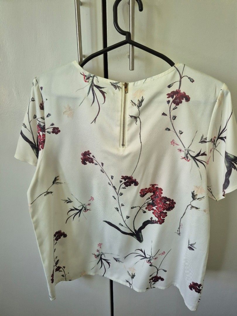 Floral Print Top with Zipper (Category: Blouses) located in Valenzuela. Submitted by pappx (Listing ID 1429764824, Image 2). Description: Top features a beautiful floral print in white with red and black accents. It has short sleeves and a zipper closure at the front. It has a round neckline and a flattering fit. Perfect for a casual day out or a semi-formal event..