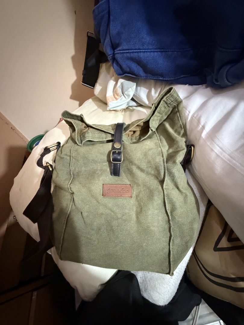 Gouache Canvas Shoulder Bag (lunch box) (Category: Shoulder Bags) located in Paranaque City. Submitted by prelovedlux83 (Listing ID 1429833564, Image 1). Description: Green canvas shoulder bag with a flap closure and adjustable strap. Features a leather accent on the flap and a small brand patch. The bag has a spacious interior. The bag has a brown strap and gold-colored hardware..