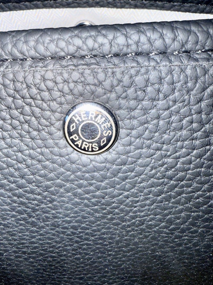 Hermes Garden Party Tote Bag (Category: Luxury Bags & Wallets) located in Quezon City. Submitted by lailah00 (Listing ID 1429774674, Image 3). Description: Black tote bag with a patterned shoulder strap. Features a silver Hermes Paris logo on the front. The interior has a zippered pocket and a light-colored lining. Includes a detachable shoulder strap. The bag has a structured shape with top handles..