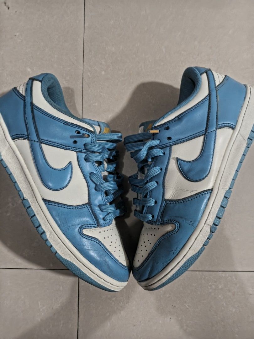 Nike Dunk Low UNC (Category: Sneakers) located in Las Pinas. Submitted by ejalaisa0018665 (Listing ID 1429779118, Image 2). Description: Nike Dunk Low in a University Blue and White colorway. Features a leather upper with a white base and blue overlays. The iconic Nike swoosh is visible on the sides. The shoe has a padded collar and tongue for comfort. The outsole is blue and the laces are blue..
