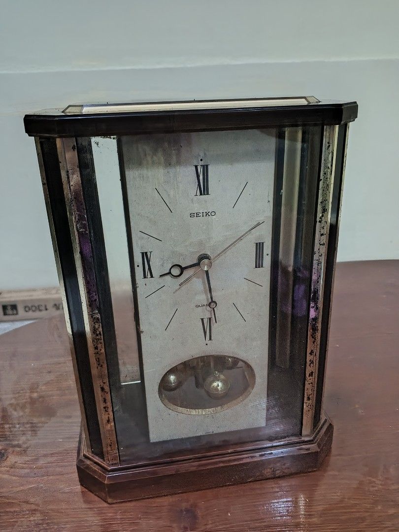 Seiko Pendulum Clock (Category: Clocks) located in Caloocan City. Submitted by surplusandbnewshop (Listing ID 1429793927, Image 1). Description: Vintage Seiko pendulum clock. Features a rectangular glass case with a wooden frame. The clock face has Roman numerals and the Seiko logo. The pendulum is visible through the glass. The back of the clock shows the clock mechanism. Requires batteries..