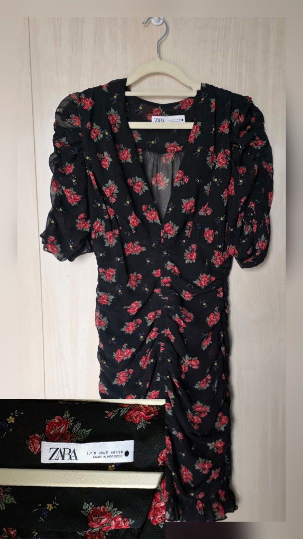 Zara Floral Dress (Category: Dresses) located in Mandaluyong City. Submitted by eli_1219 (Listing ID 1429674328, Image 1). Description: Zara floral dress with a V-neckline and ruched detailing. Features short, puffed sleeves and a knee-length hemline. The dress is black with a red floral pattern. The label is visible, confirming the Zara brand..