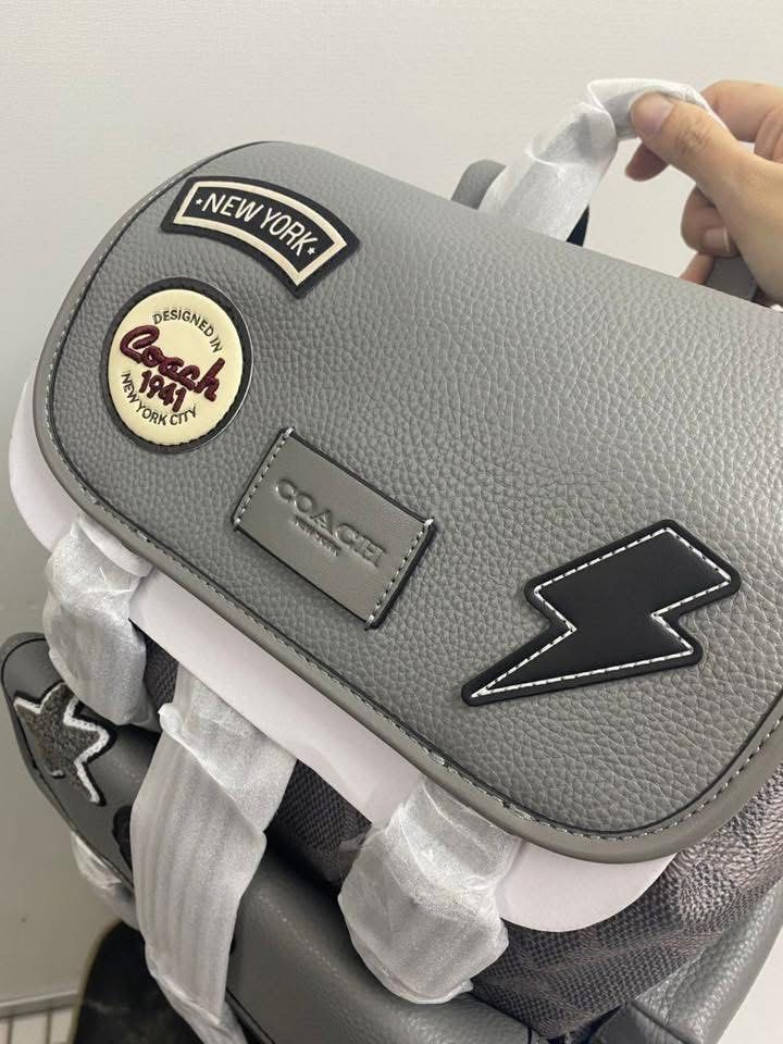 Coach Patchwork Backpack (Category: Bags & Wallets) located in Petaling Jaya. Submitted by angah_75 (Listing ID 1433352864, Image 2). Description: - Authentic Coach backpack - Grey leather exterior - Features multiple patches (star, lightning bolt) - Signature Coach pattern - Flap closure - Zippered front pocket - Adjustable shoulder straps - Breathable mesh back panel - Coach logo detail - Small zippered side pocket.