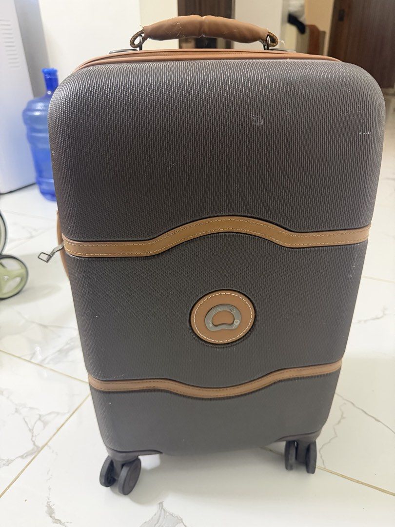 Delsey Suitcase (Category: Luggage) located in Tuguegarao City. Submitted by jeffbmad (Listing ID 1433238160, Image 2). Description: - Delsey suitcase with brown and tan accents - Retractable handle for easy maneuvering - Multiple compartments for organized packing - Includes a TSA lock for added security - Interior features a stylish red lining - Interior includes straps and zippered pockets - Exterior shows wear and tear on handles and corners 