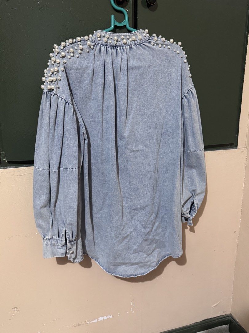 Denim Blouse with Pearl Embellishments (Category: Blouses) located in Quezon City. Submitted by AivFranc (Listing ID 1433215016, Image 2). Description: - Light wash denim blouse - Pearl embellishments on shoulders - Button-down front - Long, puffy sleeves - Round neckline - Adds a touch of elegance.