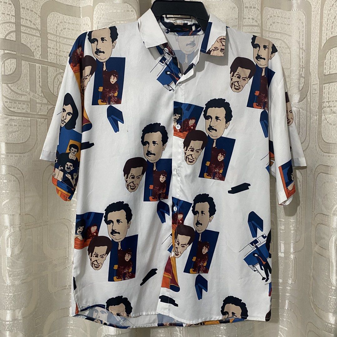 Printed Button-Down Shirt (Category: Tshirts & Polo Shirts ) located in Mabalacat. Submitted by commando07 (Listing ID 1433371923, Image 1). Description: - White button-down shirt - Unique print featuring faces and figures - Short sleeves - Classic collar - Lightweight fabric - Suitable for casual wear - Colorful and distinctive design.