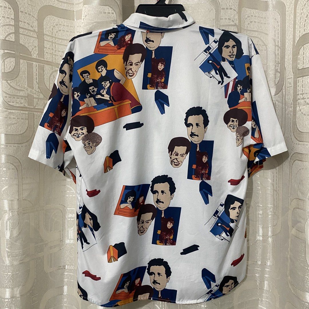 Printed Button-Down Shirt (Category: Tshirts & Polo Shirts ) located in Mabalacat. Submitted by commando07 (Listing ID 1433371923, Image 2). Description: - White button-down shirt - Unique print featuring faces and figures - Short sleeves - Classic collar - Lightweight fabric - Suitable for casual wear - Colorful and distinctive design.