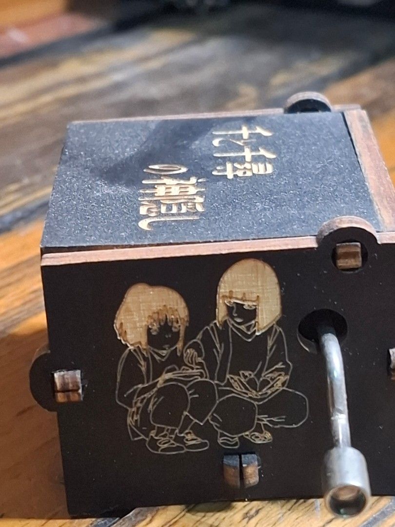 Spirited Away Music Box (Category: Vintage Collectibles) located in Manila. Submitted by riri_laine (Listing ID 1433274285, Image 3). Description: - Spirited Away themed music box - Features intricate laser-cut details - Includes characters and Japanese text - Plays a musical tune - Black box with wooden accents - "Spirited Away" text on the side.