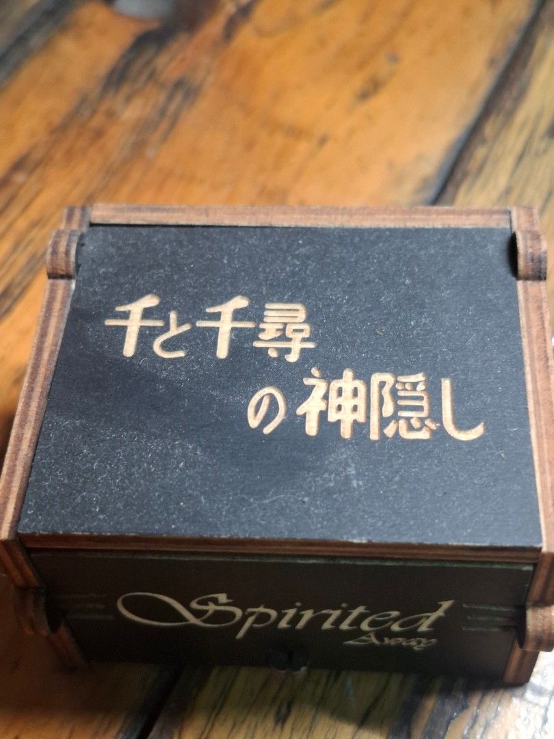 Spirited Away Music Box (Category: Vintage Collectibles) located in Manila. Submitted by riri_laine (Listing ID 1433274285, Image 2). Description: - Spirited Away themed music box - Features intricate laser-cut details - Includes characters and Japanese text - Plays a musical tune - Black box with wooden accents - "Spirited Away" text on the side.