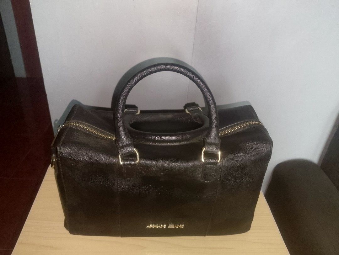 Armani Jeans Saffiano Medium Boston Bag (Category: Luxury Bags & Wallets) located in Marilao. Submitted by crisela1989 (Listing ID 1433444692, Image 2). Description: - Authentic Armani Jeans handbag - Color: Black - Design: Top handle - Hardware: Gold-tone - Closure: Zip - Includes dust bag - Interior with packaging - Features Armani Jeans logo.