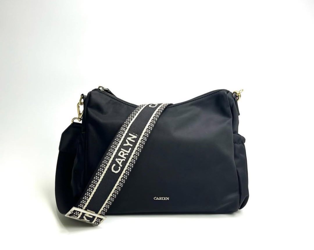 Carlyn Black Shoulder Bag (Category: Shoulder Bags) located in Baguio. Submitted by msgold2601 (Listing ID 1433576324, Image 1). Description: - Black Carlyn shoulder bag - Wide strap with brand name - Zippered main compartment - Additional side pocket - Detachable strap included - Gold-toned hardware - Black interior with Carlyn branding - Made of a nylon-like material.