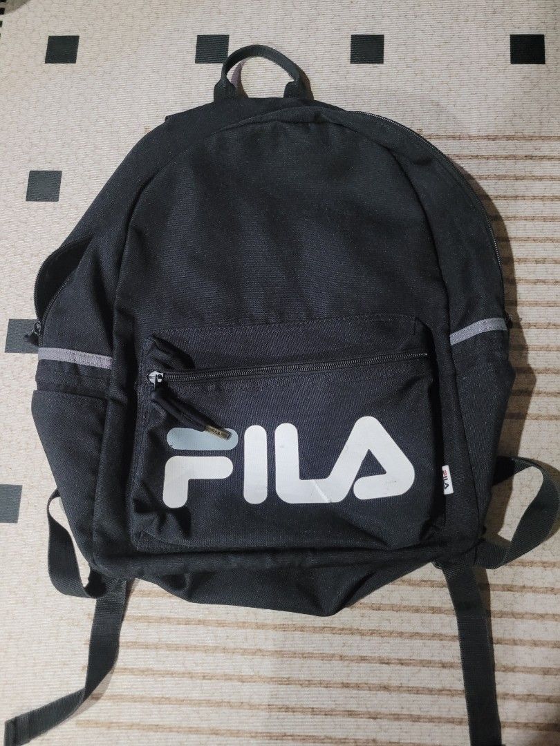 Fila Black Backpack (Category: Backpacks) located in Tanay. Submitted by happinessforless (Listing ID 1433578502, Image 2). Description: - Black Fila backpack - Front pocket with Fila logo - Adjustable shoulder straps - Top handle - Reflective strips on front and sides - Made of durable fabric - 17x12 inches.