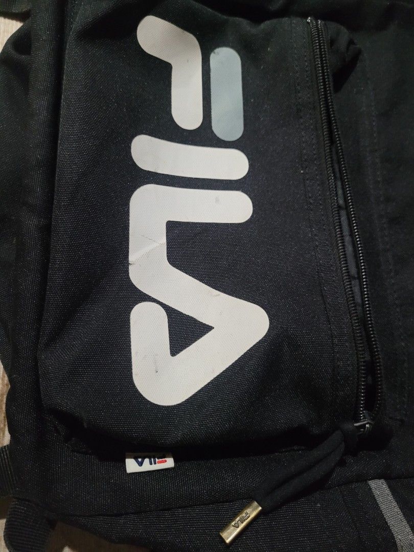 Fila Black Backpack (Category: Backpacks) located in Tanay. Submitted by happinessforless (Listing ID 1433578502, Image 3). Description: - Black Fila backpack - Front pocket with Fila logo - Adjustable shoulder straps - Top handle - Reflective strips on front and sides - Made of durable fabric - 17x12 inches.