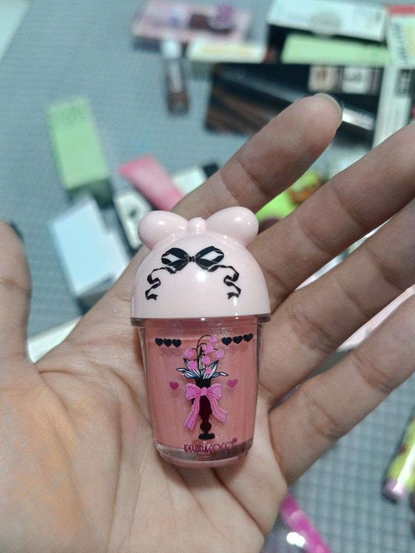 KEVIN & COCO Lip Gloss High Pigmentation Easy to Blend Shade B07 Devoted (Category: Makeup) located in Los Banos. Submitted by donnaalbay47990 (Listing ID 1433578361, Image 3). Description: KEVIN & COCO lip gloss in shade B07 Devoted. The lip gloss has a cute, pink, ice cream cup-shaped container with a bow design. The packaging includes a matching pink box with the brand name and product details..