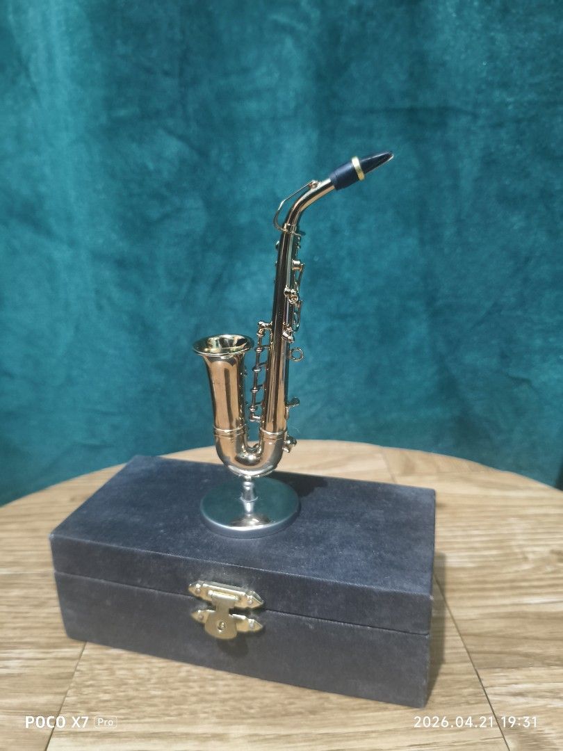 Miniature Saxophone with Case (Category: Musical Instruments) located in Baguio. Submitted by baguiobeans (Listing ID 1433509415, Image 2). Description: - Miniature gold-colored saxophone - Includes a stand - Comes with a black case - Detailed design - Decorative item - Small, handheld size - Case features a clasp.