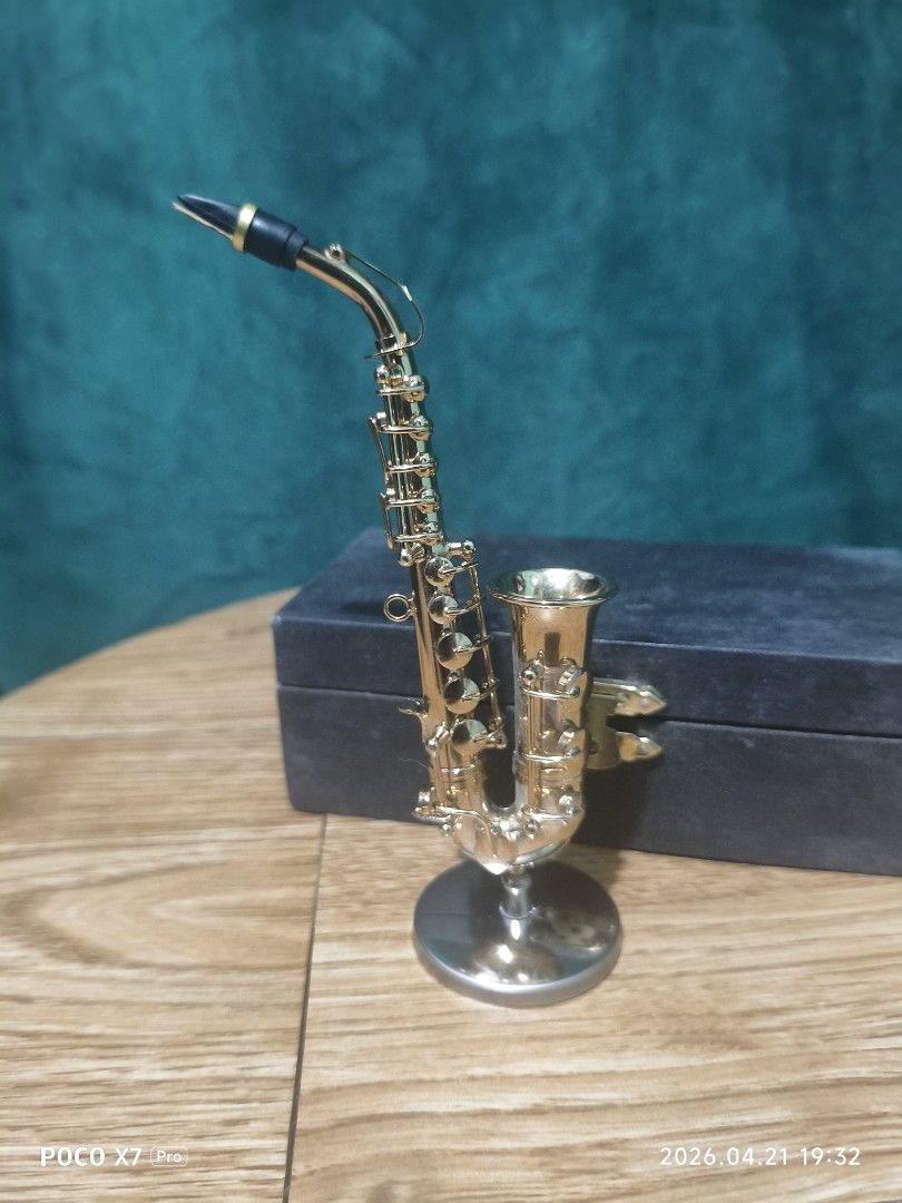 Miniature Saxophone with Case (Category: Musical Instruments) located in Baguio. Submitted by baguiobeans (Listing ID 1433509415, Image 1). Description: - Miniature gold-colored saxophone - Includes a stand - Comes with a black case - Detailed design - Decorative item - Small, handheld size - Case features a clasp.