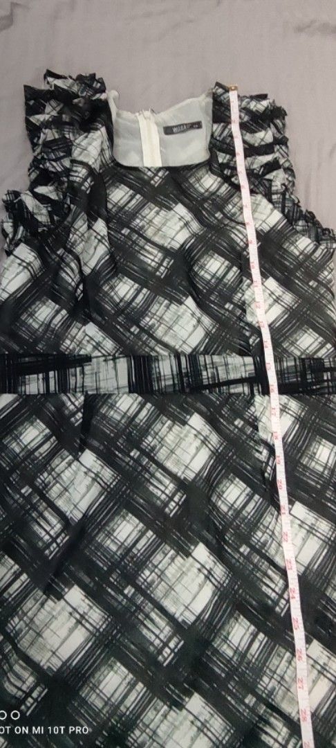 MNG Black and White Dress (Category: Dresses) located in Cavite. Submitted by Combiishop (Listing ID 1433454980, Image 2). Description: - Sleeveless dress - Black and white plaid pattern - Ruffled neckline - Fitted waist - Flared skirt - Zipper closure - Approximately 35 inches in length - Brand tag visible.