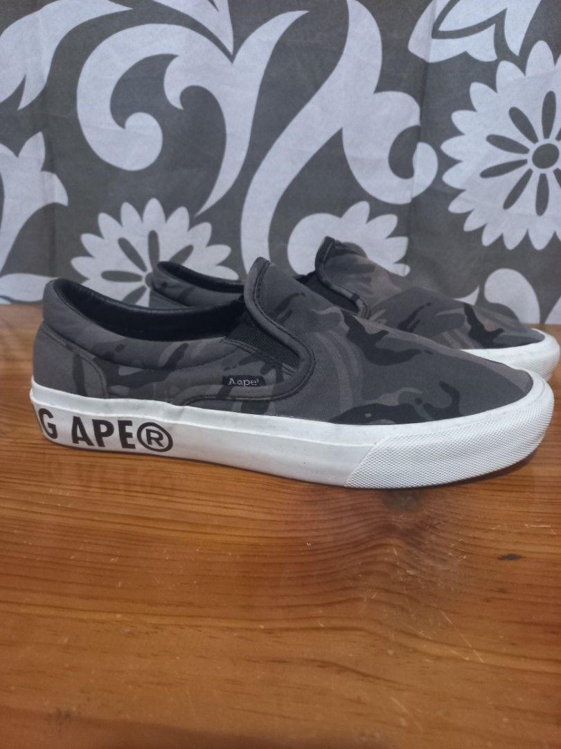 Aape by A Bathing Ape Camo Slip-On Sneakers 8.5US (Category: Sneakers) located in Baguio. Submitted by highticket75 (Listing ID 1433605586, Image 3). Description: - Aape by A Bathing Ape slip-on sneakers - Camouflage pattern - White sole with "AAPE BY A BATHING APE" branding - Insole: Aape logo and size details - Size: US 8.5 / EUR 42 / JP 265 / CHN 265(3.0) - Style Code: AAPSHM6677XXE - Color: BKZ.