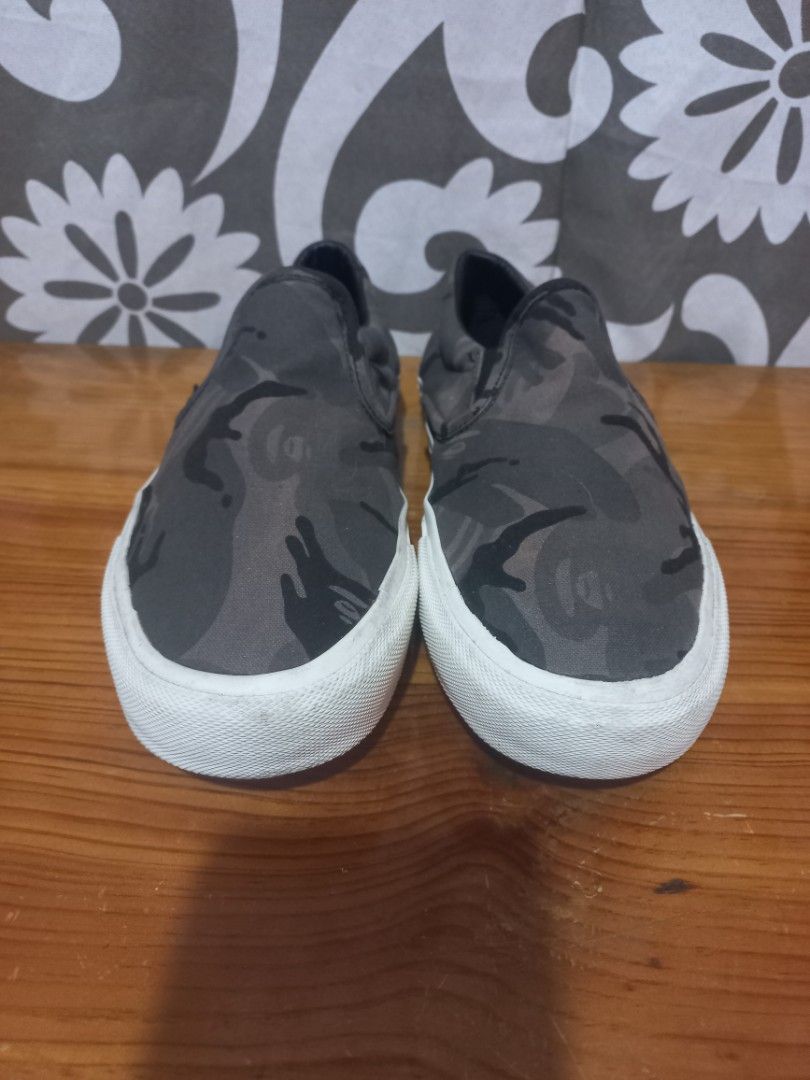 Aape by A Bathing Ape Camo Slip-On Sneakers 8.5US (Category: Sneakers) located in Baguio. Submitted by highticket75 (Listing ID 1433605586, Image 2). Description: - Aape by A Bathing Ape slip-on sneakers - Camouflage pattern - White sole with "AAPE BY A BATHING APE" branding - Insole: Aape logo and size details - Size: US 8.5 / EUR 42 / JP 265 / CHN 265(3.0) - Style Code: AAPSHM6677XXE - Color: BKZ.