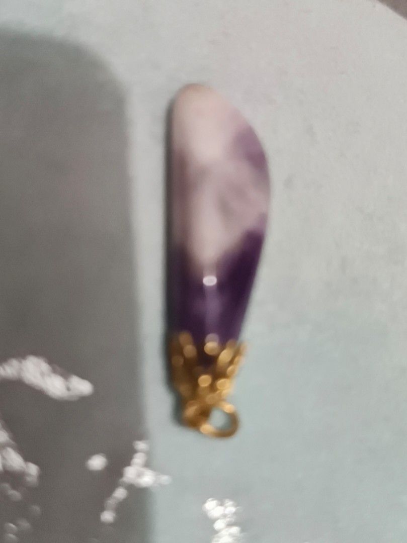 Amethyst Pendant with Gold Accents (Category: Charms) located in Binan City. Submitted by maydenseven2006 (Listing ID 1433759738, Image 1). Description: - Beautiful amethyst pendant - Gold-colored metal accent - Polished, elongated shape - Gradient of purple and white hues - Includes a loop for easy attachment - Unique and elegant design.