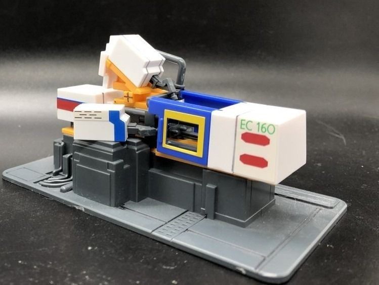 Bandai 1/60 Gundam Gunpla Hobby Center Original Electromotive Style Injection Machine (Category: Gundam Model Kits) located in Singapore. Submitted by suntrailerhobby (Listing ID 1433783392, Image 3). Description: The Bandai Hobby Center Original 1/60 Electromotive Style Injection Machine is a unique "Gunpla of a machine that makes Gunpla". It is a 1/60 scale replica of the actual four-color injection molding machines used at the Bandai Hobby Cen