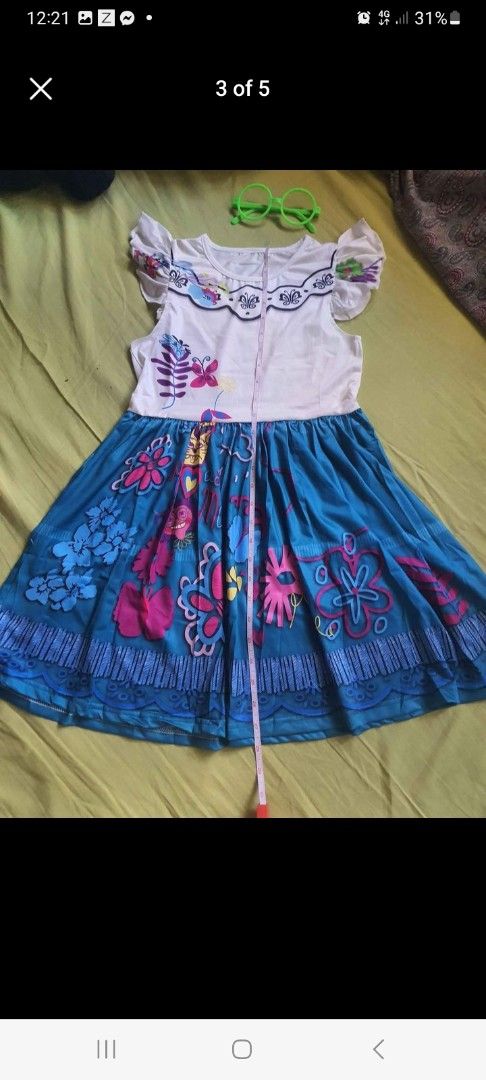 Encanto Dress with Accessories (Mirabel) (Category: Babies & Kids Fashion) located in Pasig City. Submitted by peppermintpatty_1221 (Listing ID 1433778241, Image 2). Description: - Encanto-themed dress - White top with floral accents - Blue skirt with vibrant floral patterns - Includes matching handbag - Comes with green glasses - Perfect for dress-up or themed parties.