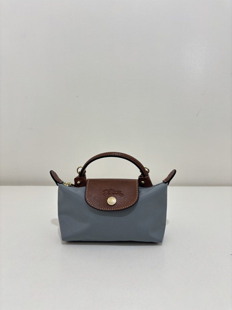 Longchamp Le Pliage Cuir Mini Bag (Category: Luxury Bags & Wallets) located in Dagupan City. Submitted by raregrail.co (Listing ID 1433698624, Image 1). Description: - Authentic Longchamp Le Pliage Cuir Mini Bag - Color: Grey - Brown leather flap and handles - Detachable shoulder strap - Gold-tone zipper and hardware - Made in France - Interior label with Longchamp logo - Stylish and versatile for everyday use.