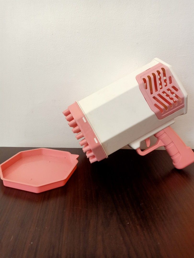 Pink Bubble Gun (Category: Kids Toys) located in Las Pinas. Submitted by the_recycle_shop (Listing ID 1433629827, Image 1). Description: - Pink bubble gun - Includes octagonal tray - White and pink color scheme - Features a trigger and multi-hole nozzle.