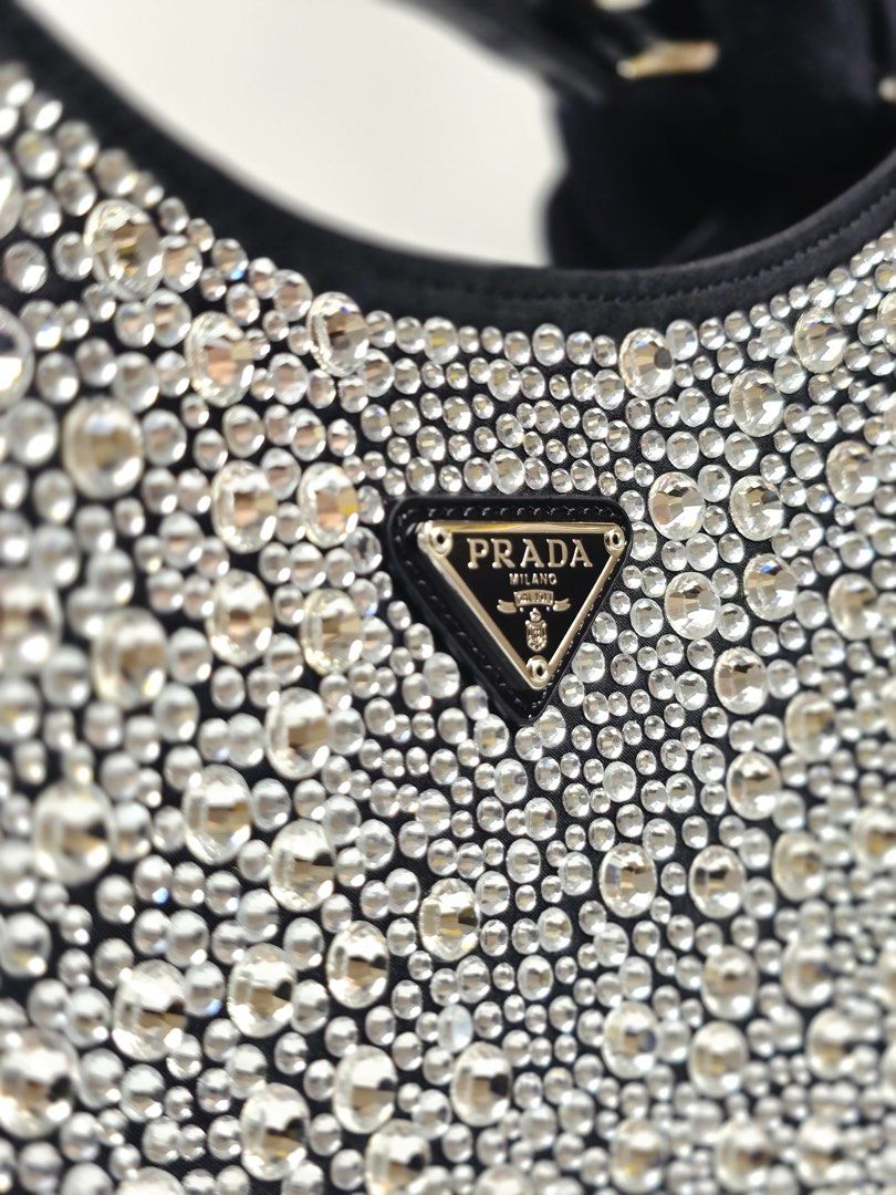Prada Cleo Crystal Satin (Category: Luxury Bags & Wallets) located in Pandi. Submitted by luximperium (Listing ID 1433601348, Image 3). Description: Color: Black with crystal embellishments Includes: Dust bag, Info Booklet/Care Card Material: Leather, Satin, Silver Sequins Stones (Exterior), Satin (Interior) Size: Small Dimensions: L (22cm), H (18cm), W (4.5cm), HD (8.5cm) Condition: Excellent. Others: All-over synthetic crystals; Adjustable leat