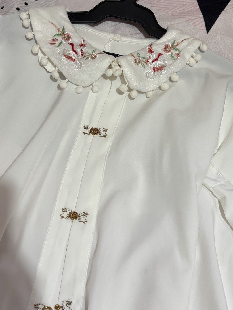 White Embroidered Peter pan Collar Blouse (Category: Blouses) located in San Mateo. Submitted by angelthings.cute (Listing ID 1433677520, Image 3). Description: - Elegant white blouse - Embroidered collar with pom-pom trim - Long sleeves - Decorative button closures - Floral embroidery on collar - Slight flare on sleeves - Lightweight fabric.