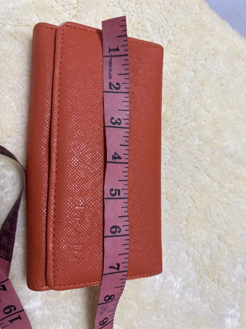 2027 Prada Orange Wallet (Category: Luxury Bags & Wallets) located in Silang. Submitted by sari2bilina (Listing ID 1433940897, Image 1). Description: - not sure if Authentic Prada orange wallet - Multiple card slots and cash compartments - Includes a zippered pocket - Crafted from textured leather - Interior lining with Prada logo - Secure snap closure - Clear ID window with flaws last 2 pics .