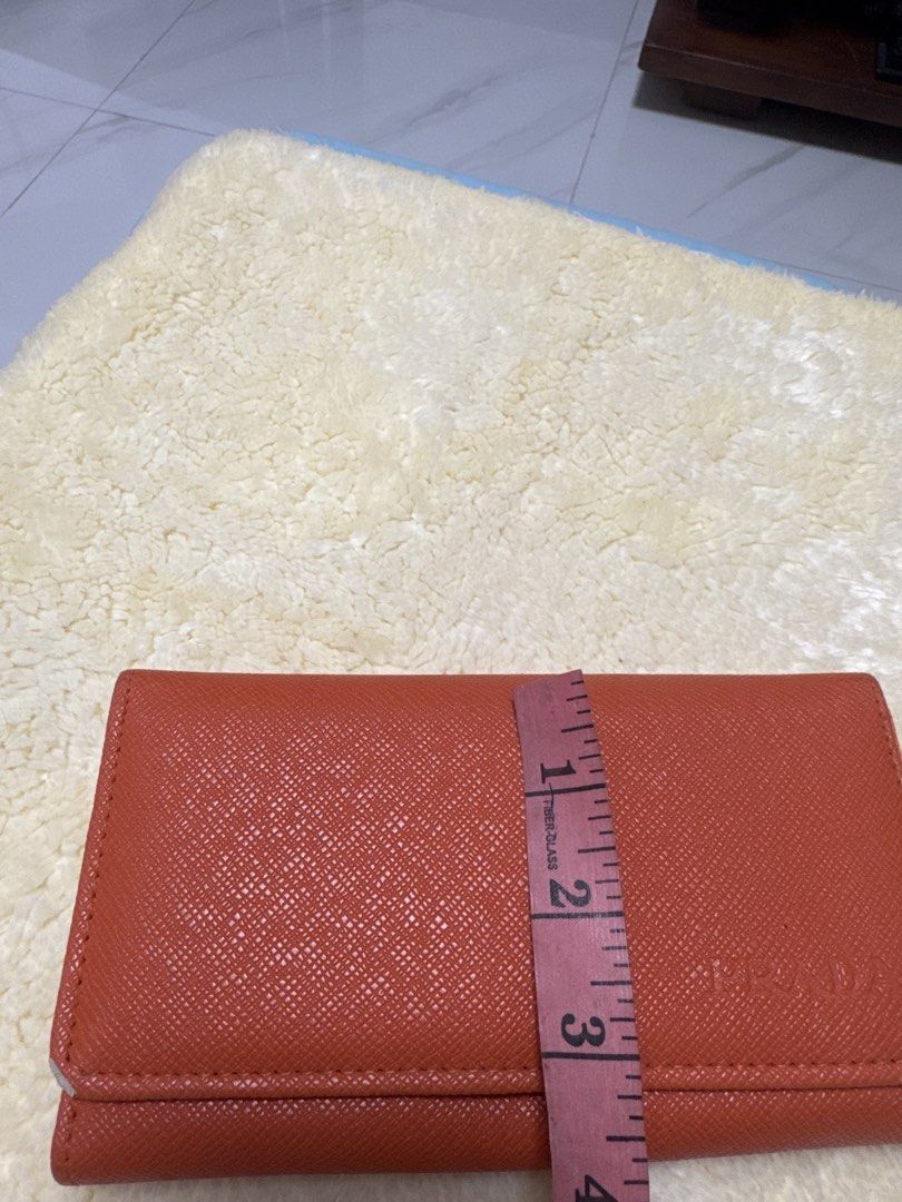 2027 Prada Orange Wallet (Category: Luxury Bags & Wallets) located in Silang. Submitted by sari2bilina (Listing ID 1433940897, Image 2). Description: - not sure if Authentic Prada orange wallet - Multiple card slots and cash compartments - Includes a zippered pocket - Crafted from textured leather - Interior lining with Prada logo - Secure snap closure - Clear ID window with flaws last 2 pics .