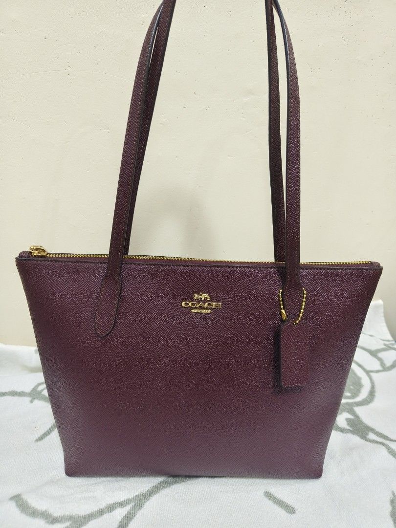 Coach Fiona Tote Bag small (Category: Luxury Bags & Wallets) located in Rizal. Submitted by ortegaalex06291 (Listing ID 1433969309, Image 1). Description: - Maroon Coach tote bag - Gold-tone hardware - Zip closure - Includes Coach hang tag - Features Coach label - Structured shape - Long handles for shoulder carry - Textured, leather-like exterior material.