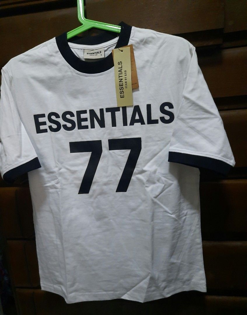 Essentials Fear of God 77 T-shirt (Category: Tshirts & Polo Shirts ) located in Makati City. Submitted by fiercecat_1521ja (Listing ID 1433884035, Image 1). Description: - White t-shirt with black accents - Features "ESSENTIALS" printed on the front - Includes "77" in large black font - Black collar and sleeve trim - Size: S (for men's size) - Comes with original tag.