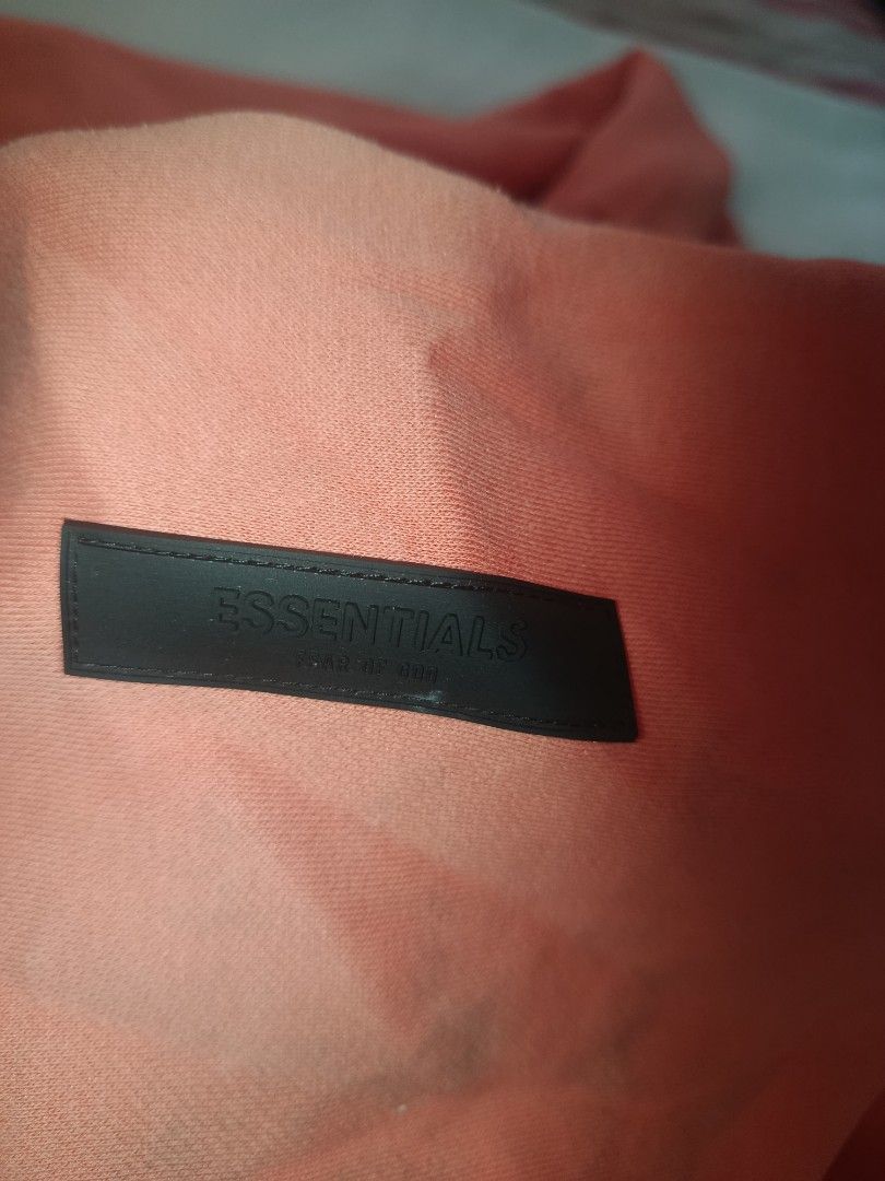 Essentials Fear of God Hoodie (Category: Hoodies) located in Caloocan City. Submitted by livedeer-1208c7 (Listing ID 1433823382, Image 2). Description: - Essentials Fear of God hoodie - Coral/Salmon color - Features the Essentials logo on the front - Kangaroo pocket - Hood - Essentials label visible inside.
