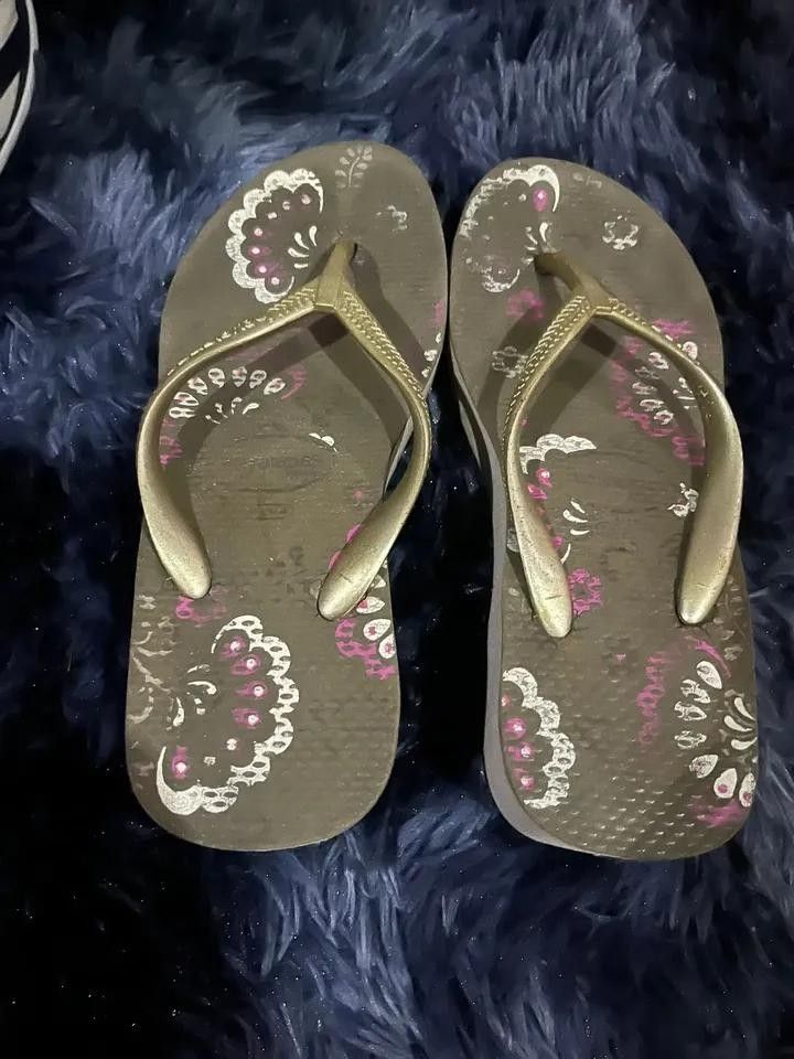 Havaianas Wedge Flip-flops (Category: Slippers and slides) located in Mandaluyong City. Submitted by indapresci39774 (Listing ID 1433840859, Image 2). Description: - Havaianas wedge flip-flops - Floral design footbed - Gold straps - Wedge heel for added height and comfort - Signs of wear on footbed and straps - Ideal for casual wear and beach trips.