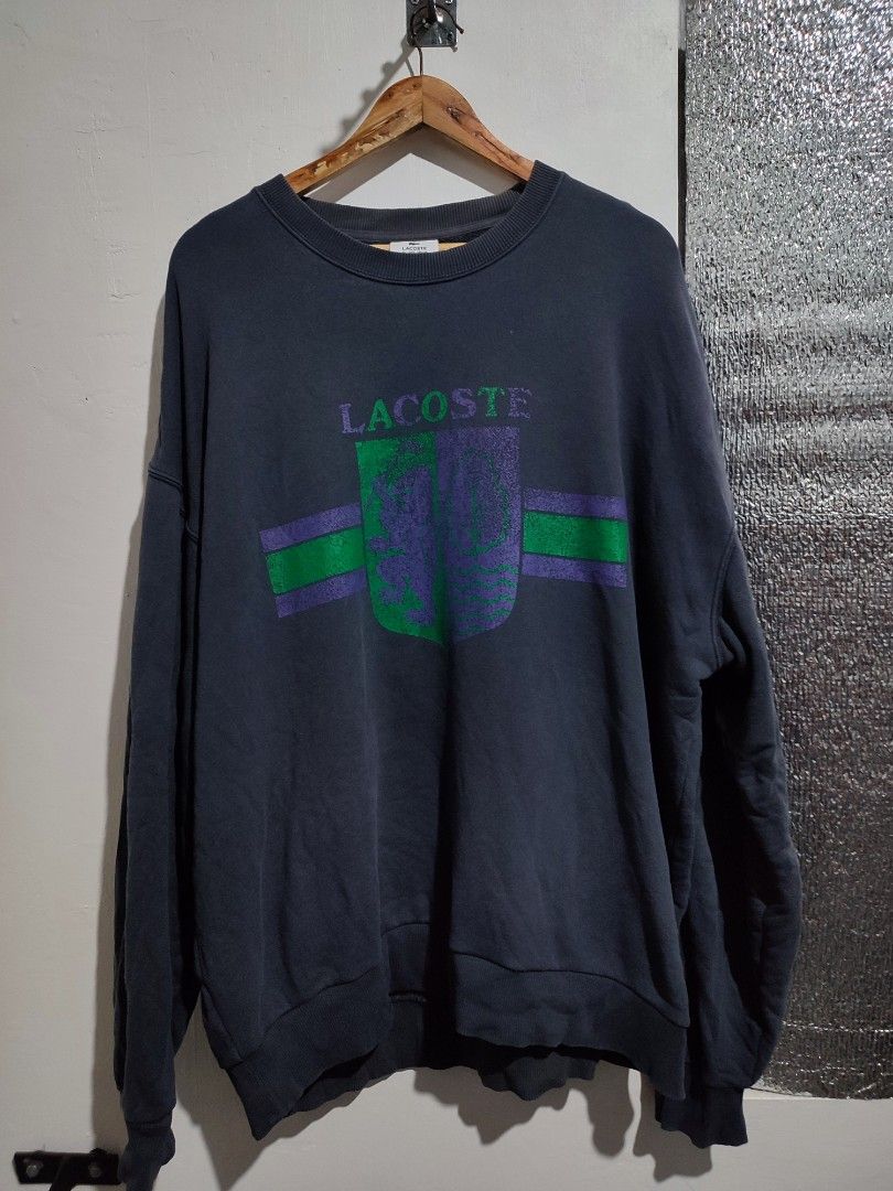Lacoste Crewneck Sweatshirt (Category: Coats, Jackets and Outerwear) located in Caloocan City. Submitted by solestreetclub (Listing ID 1433840581, Image 2). Description: - Dark blue Lacoste crewneck sweatshirt - Features Lacoste logo on front - Shield design with green and purple stripes - Small Lacoste logo on back - Classic crew neck - Long sleeves Dimes: 24-25 X 30 Color: Gray Color rate: 9.5 / 10.